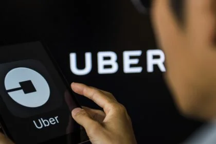 young man holds a smart device while using uber app 858492232 5b32d1884cedfd0037f8117a